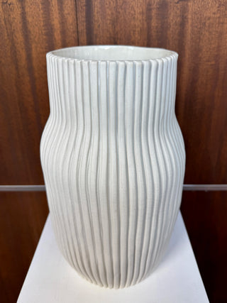 White ribbed vase on wood background