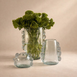 Set of three glass vases with unique designs on a beige background