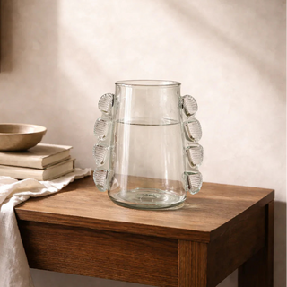 Glass vase on a wooden side table with soft lighting