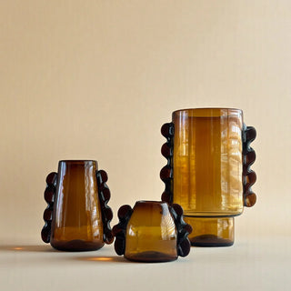 Three amber-colored glass vases on a beige background