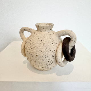 Speckled ceramic vase with handles on a white surface