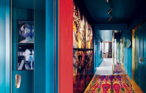 Colorful hallway with blue walls, a red door, and a patterned rug.