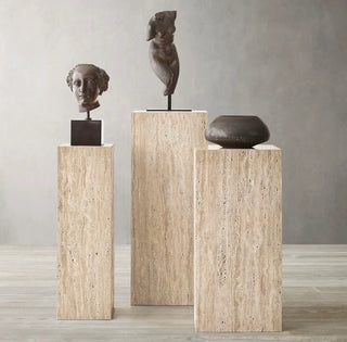 Three stone sculptures on travertine pedestals 