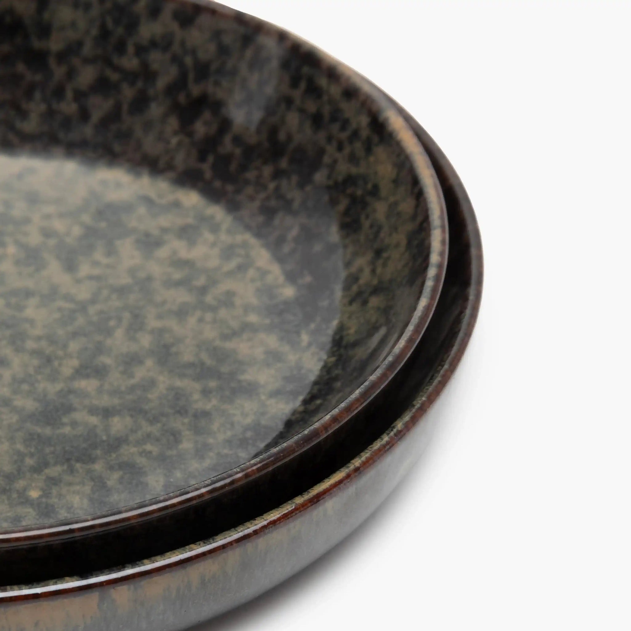 Two stacked ceramic plates with a speckled glaze on a white background