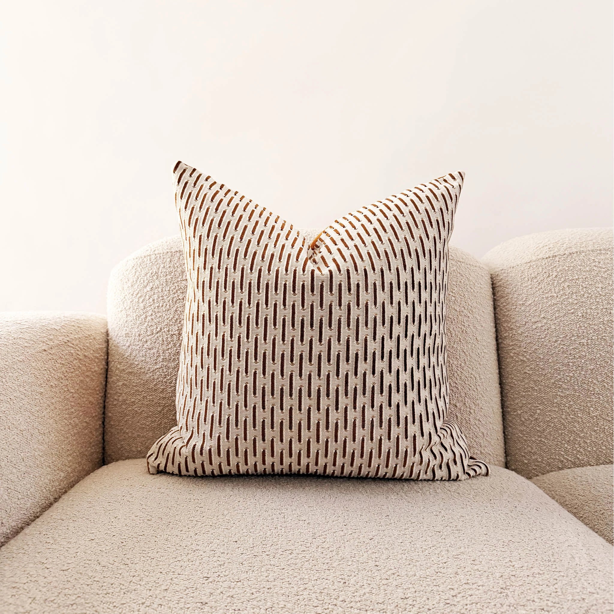 Patterned pillow on a beige sofa against a white background