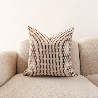 Patterned pillow on a beige sofa against a white background