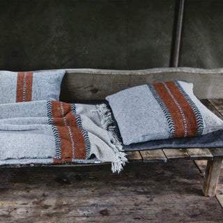 Gray and brown striped blanket and pillow on a wood bench