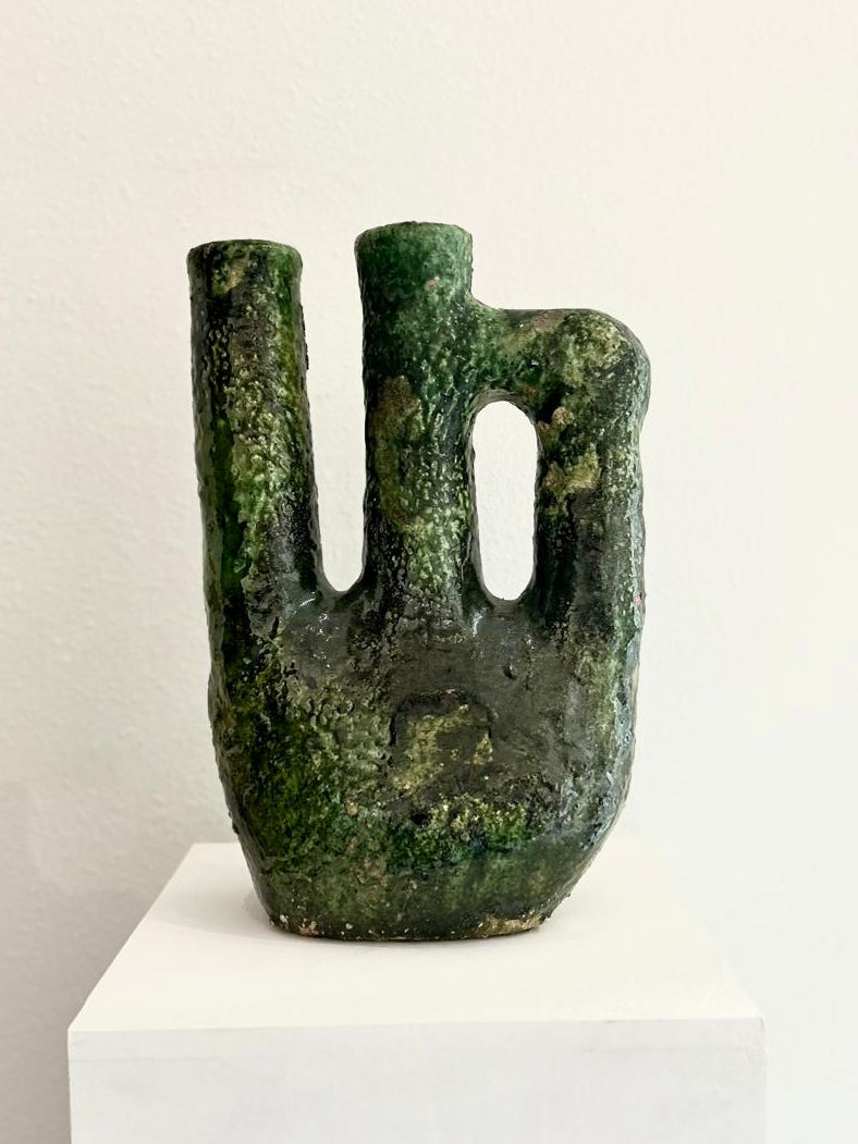 Greenish-brown abstract sculpture on a white pedestal 