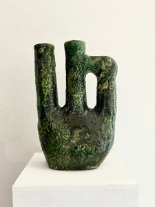 Greenish-brown abstract sculpture on a white pedestal 