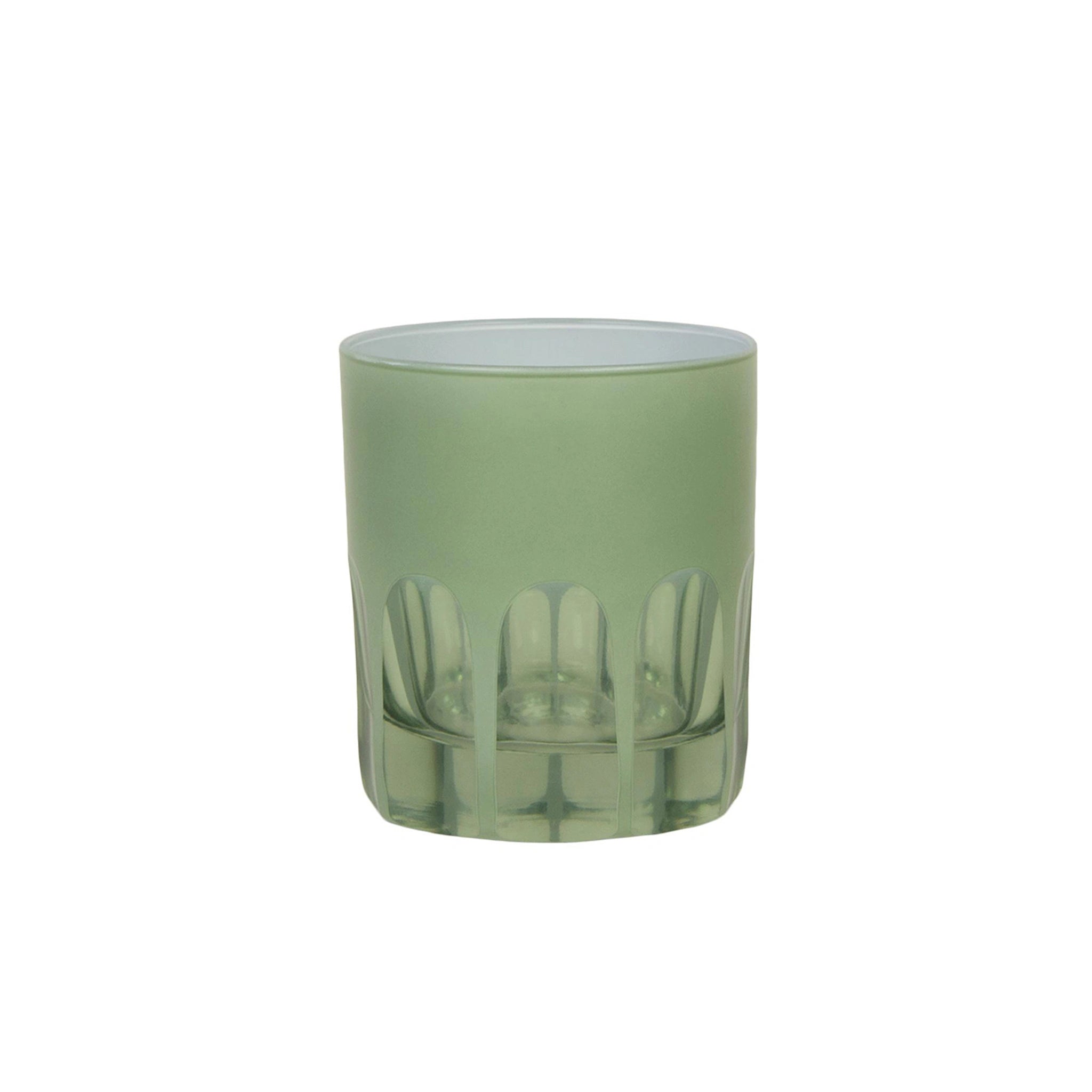 Green glass tumbler with cut-out design on a white background