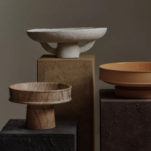Three stone bowls of different sizes on elevated platforms against a dark background