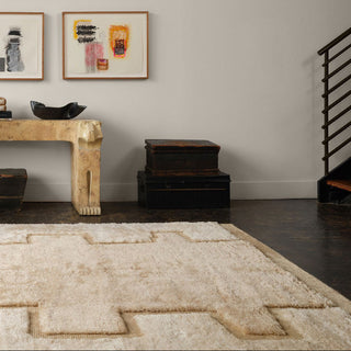 Room interior with a textured rug, wooden console table, and framed artwork on the wall.