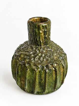A small textured ceramic vase with a bulbous rounded body, flared neck, and ribbed base, covered in a glossy mossy green glaze with brown and gold highlights, set against a plain white background.