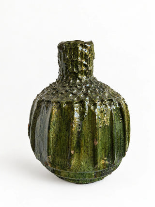 A small textured ceramic bottle with a ribbed, bulbous body and short neck, featuring a glossy dark green and brown glaze, set against a plain white background.