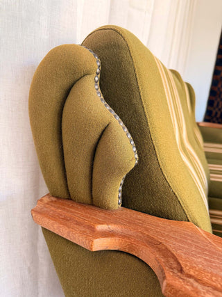 Close-up of a green upholstered vintage sofa with wooden armrest 