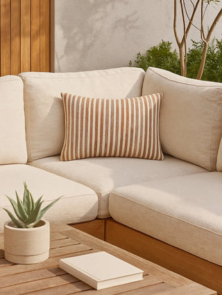 Beige sectional sofa with a striped pillow on an outdoor patio.