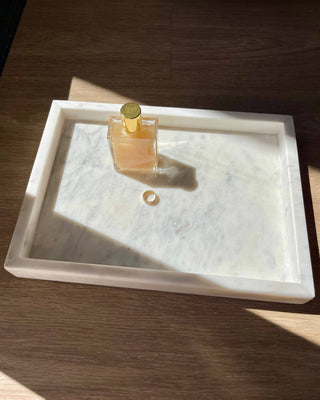 Perfume bottle on a marble tray with a wooden background