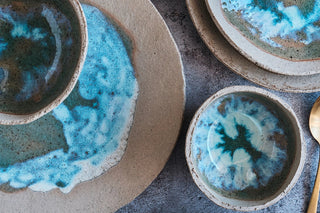 Set of ceramic bowls with blue and green glaze on a textured surface