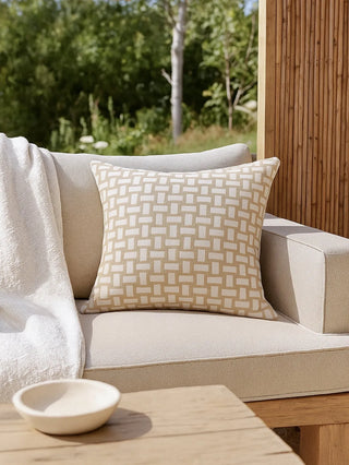 Beige outdoor sofa with a patterned pillow and a wooden table in a garden setting