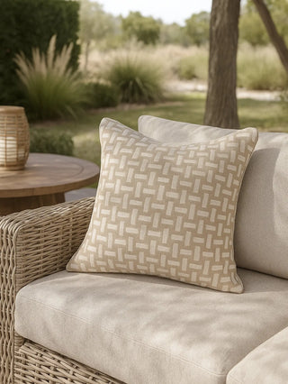 Beige outdoor pillow on a wicker chair with a garden background