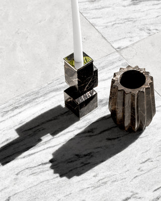 Duna sculptural flower vase made from Monterrey black marble with white veining hand-carved in Mexico shown with marble candlestick holder