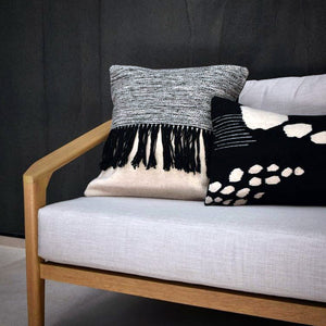 Almata rectangular kidney throw pillow in a black and white contemporary organic design hand-woven in wool on a pedal loom in Oaxaca, Mexico shown sitting on a sofa