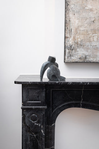 Latona bronze sculptural art form sitting on black marble fireplace features curves contrasting with sharp corners